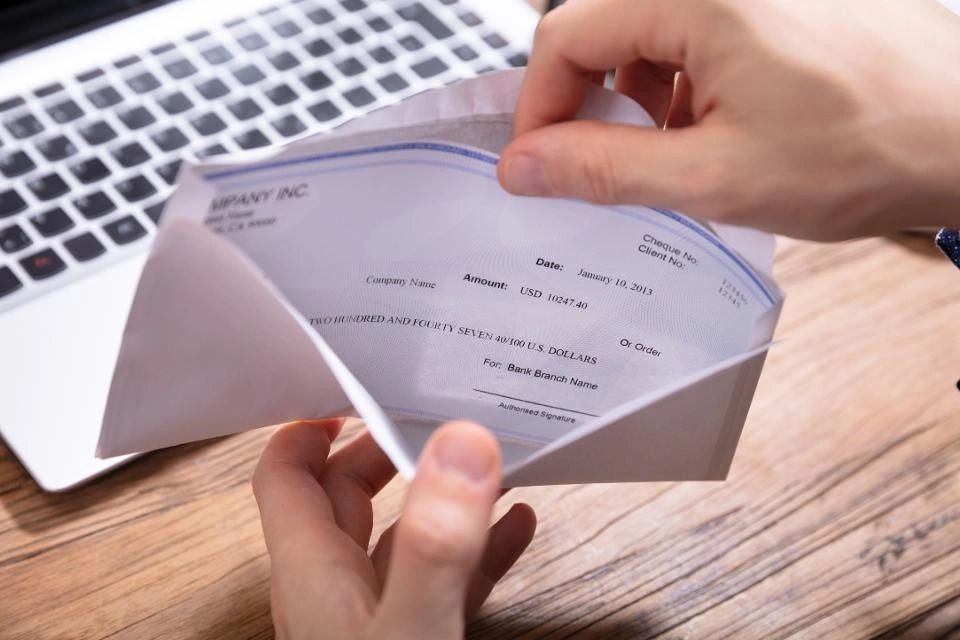 Man opening envelope containing paycheck